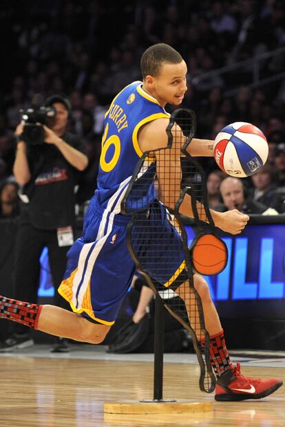 El jugador de los Warriors de Golden State Stephen Curry evade unos obstáculos. Curry ganó el concurso de habilidades, una especie de yincana contrarreloj en la que el jugador debe anotar un tiro, efectuar un eslalon entre figuras, hacer pasar el balón previo bote por dos aros antes de encarar el aro y anotar con un mate.