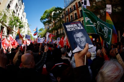 Un manifestante muestra el libro de Pedro Sánchez 'Manuel de resistencia' durante la concentración en los alrededores del partido.