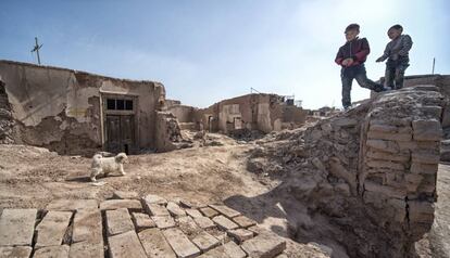 Dos niños recorren con una cría de perro la zona demolida del casco antiguo de Kashgar.