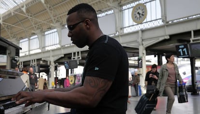 Un hombre sentado al piano de la estación de Lyon.