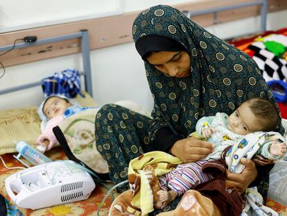Una mujer palestina, con sus hijas gemelas, que sufren desnutrición, el día 12 en un centro de salud en Rafah, en el sur de Gaza.