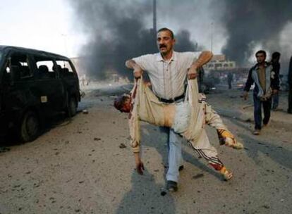 Un hombre traslada el cuerpo de una víctima del atentado de ayer en un mercado de Bagdad.