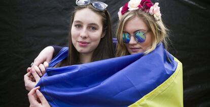 Dos chicas ucranias, residentes en La Haya, se cubren con la bandera de su pa&iacute;s, en una manifestaci&oacute;n en &Aacute;msterdam.