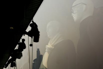 Operarios limpian los cristales de un centro comercial de Pekín (China) ante la mirada de dos maniquíes.