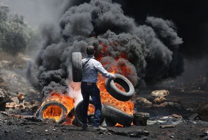 Un manifestante palestino lanza neumáticos en un hoguera durante una protesta cerca de la ciudad de Nablus (al norte de Cisjordania).