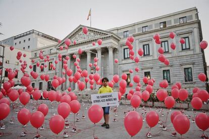 Said, un niño sirio de 8 años, muestra un cartel durante el acto organizado por Save the Children a las puertas del Congreso de los Diputados, en Madrid.