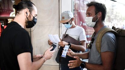Un espectador muestra su pasaporte sanitario en la entrada de un cine en París.