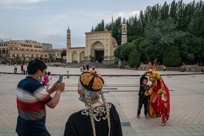 Frente a la mezquita de Id Kah, a la hora de la oración que precede al Iftar, un joven uigur se hace una fotografía con un personificador del Rey Mono, héroe de la fábula china 'El viaje al oeste', el 9 de abril en Kasgar.