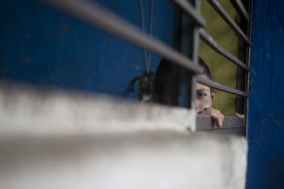 Un niño mira a través de las rejas de una de las habitaciones-celda del albergue.