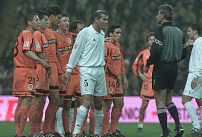 Zidane se sitúa delante de la barrera del Valencia, que le protesta al árbitro.