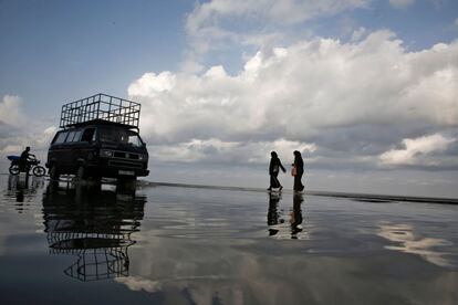 Dos mujeres cruzan una carretera inundada, cerca de una playa de Gaza.