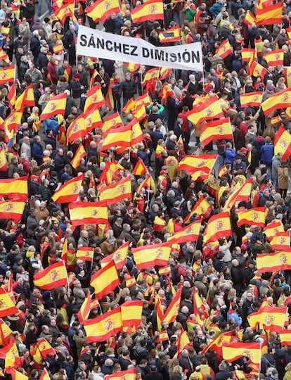 Manifestantes com bandeiras espanholas e um cartaz com o lema "Sánchez demissão", na manifestação na praça de Colón de Madri.