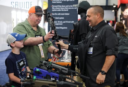 Un hombre sostiene un arma mientras un niño observa, en la convención anual de la Asociación Nacional del Rifle en Houston, Texas, este viernes. El encuentro se ha producido a unos 400 kilómetros del lugar de la matanza perpetrada por Salvador Ramos hace apenas cuatro días.