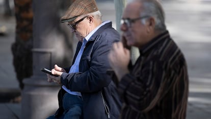 Two men using their mobile phones in Seville.