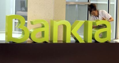 Una operaria limpia el logo de Bankia.