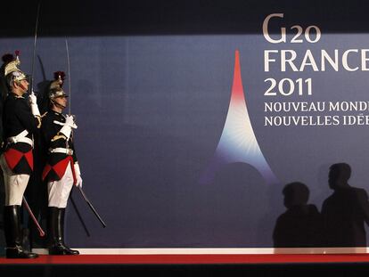 Las sombras de Angela Merkel y Nicolas Sarkozy se proyectan sobre el cartel de la cumbre del G-20, que ayer comenzó en la ciudad francesa de Cannes.