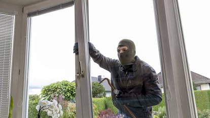 Un ladrón intenta entrar por la ventana de una casa, forzándola.