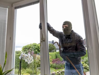 Un ladrón intenta entrar por la ventana de una casa, forzándola.