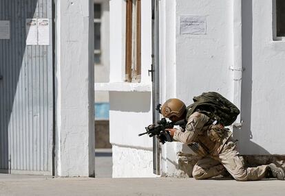 Un miembro de las fuerzas de seguridad afganas apunta con su fusil en el lugar donde se han producido enfrentamientos contra los insurgentes tras un ataque suicida en una mezquita de Kabul (Afganistán).