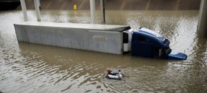 Homens nadam em uma autopista alagada em meio a alagamento provocado pelo furacão em Houston.