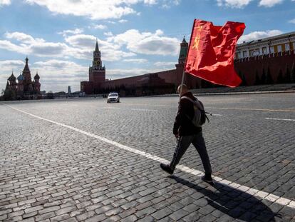 A Russian Communist party supporter carries a red flag as he walks along Red Square in Moscow on May 1, 2020. - The Labour Day celebrations were cancelled due to pandemic threat of Covid-19. (Photo by Yuri KADOBNOV / AFP)