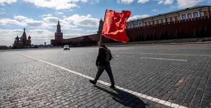 A Russian Communist party supporter carries a red flag as he walks along Red Square in Moscow on May 1, 2020. - The Labour Day celebrations were cancelled due to pandemic threat of Covid-19. (Photo by Yuri KADOBNOV / AFP)