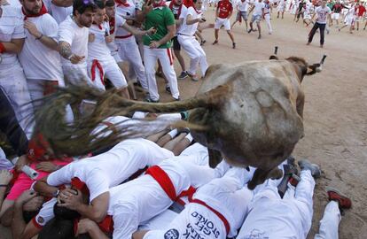 Uno de los toros salta sobre los mozos durante este sexto encierro ya en la plaza de toros de Pamplona.