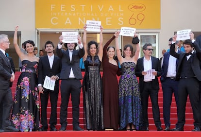 El director brasileño Kleber Mendonca Filho y el elenco de la película "Aquarius" sostienen carteles que rezan "Brasil experimenta un golpe de estado" en el Festival de Cine Internacional de Cannes.