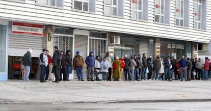 Varias personas forman una larga cola ante una oficina del INEM