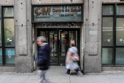Dos personas ante la puerta principal del centro de salud Las Cortes, en el distrito Centro de Madrid, este martes.