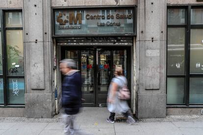 Dos personas ante la puerta principal del centro de salud Las Cortes, en el distrito Centro de Madrid, este martes. 