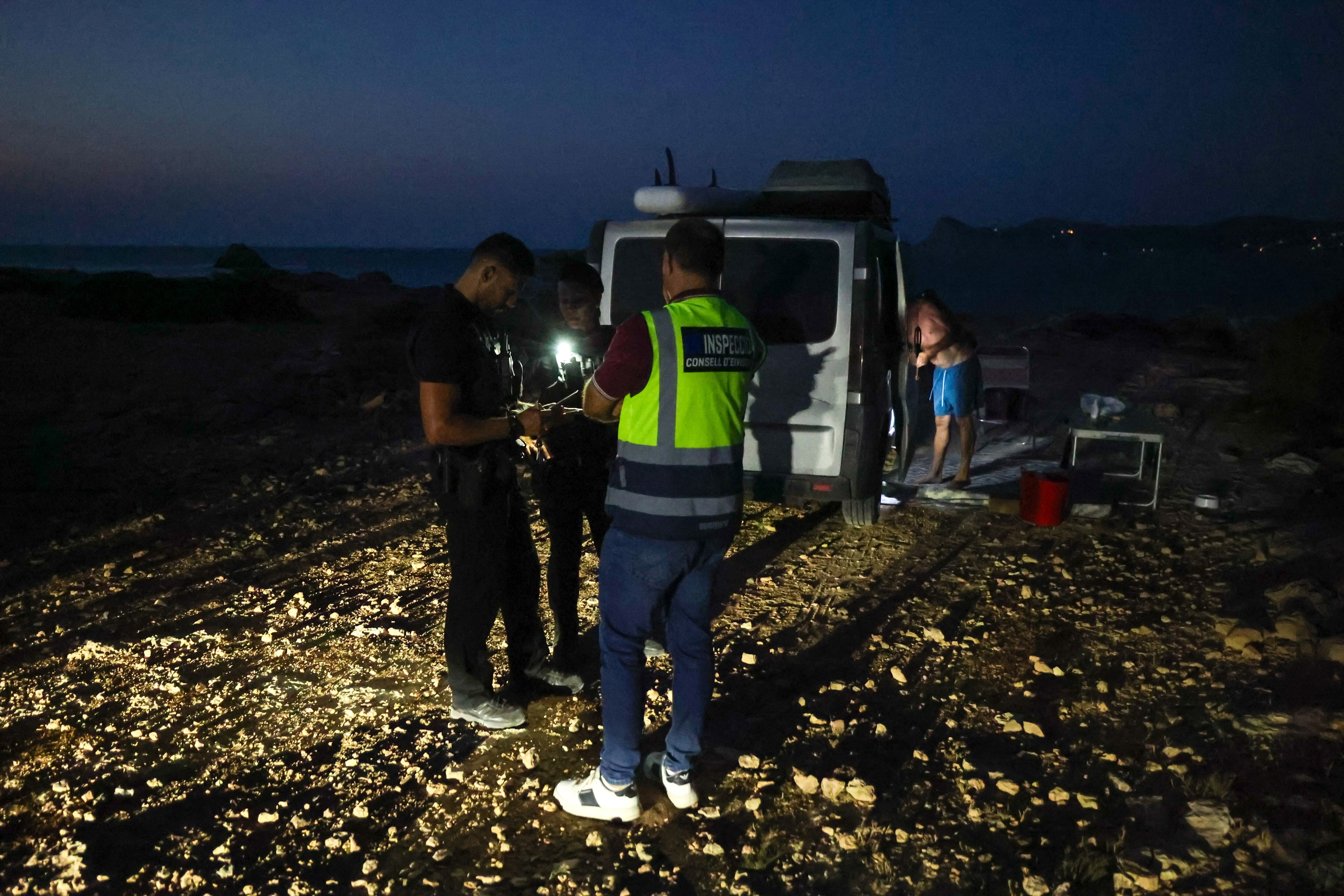 Una pareja de policías locales de San José y un inspector de Transportes del Consell comprueban los permisos de una caravana en Torre D'en Rovira.