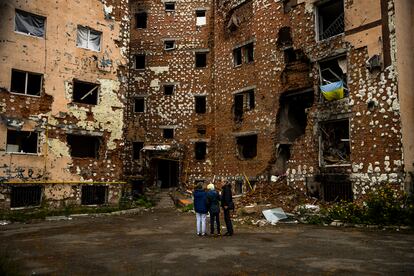 Misha y sus padres frente a unos edificios destruidos en Bucha (Ucrania).