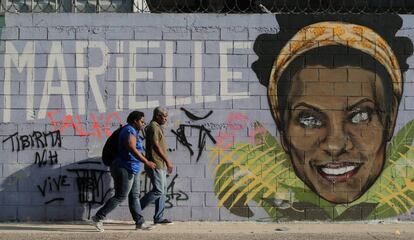 Dois transeúntes ante um grafiti de Marielle Franco, o vereador assassinada faz em um ano em Rio.