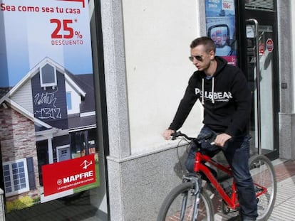 Un ciclista pasa delante de una oficina de Mapfre, en Madrid.