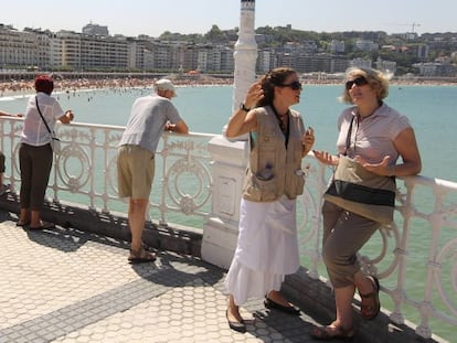 Algunos turistas disfrutan del sol en la playa donostiarra de la Concha