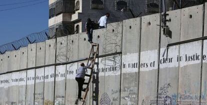 Varios palestinos saltan el muto de separación cerca de Jerusalén.