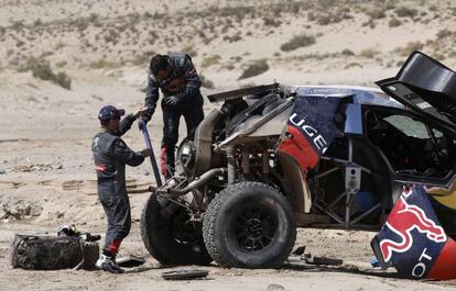 Loeb y Elena reparan el Peugeot.