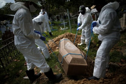 Varios sepultureros con equipos de protección entierran a una víctima de coronavirus, en Marajó (Brasil).