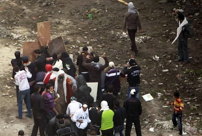 Unos manifestantes se protegen con tablas de madera mientras se enfrentan a las fuerzas de seguridad