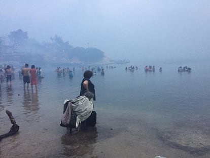 Las personas se sumergen en el mar para huir de las llamas del incencio forestal en Mati, en los alrededores de Atenas (Grecia).