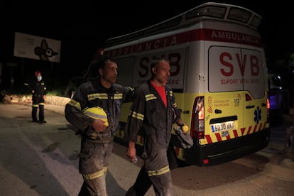 Dos bomberos tras rescatar con vida a una de las personas sepultadas. Detrás, la ambulacia en la que ha sido trasladada.