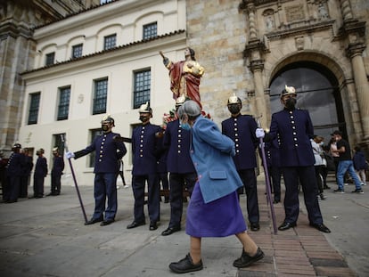 Una mujer camina junto a un grupo de penitentes que cargan una efigie de Cristo durante el pasado viernes santo, en Bogotá.
