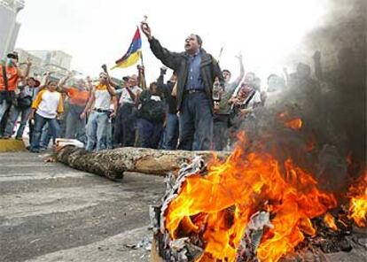 Varios manifestantes antichavistas se manifiestan ante una barricada incendiada en Caracas