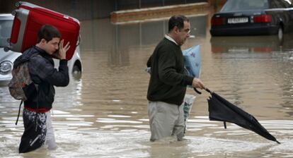 Dos vecinos de Écija sacan enseres de su vivienda por la crecida del río Genil.