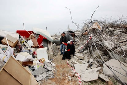 Una mujer palestina llora sentada sobre las ruinas de su casa y los restos de sus pertenencias.
