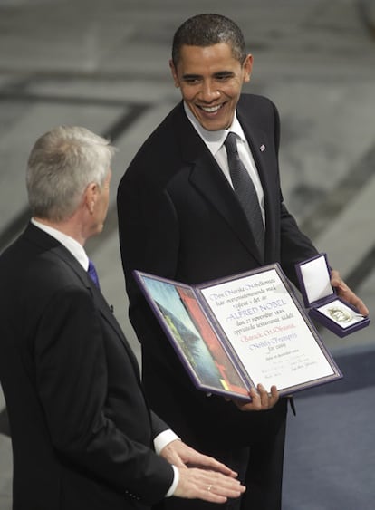 El mandatario estadounidense posa sonriente con la medalla y el diploma que le ha entregado el presidente del Comité, Thorbjorn Jagland, a la izquierda.