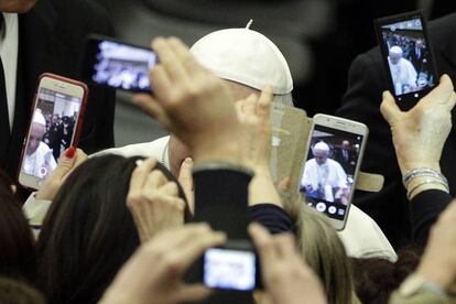 Un grupo de fieles utilizan sus teléfonos móviles para fotografiar al papa Francisco durante una audiencia general semanal en el Vaticano.