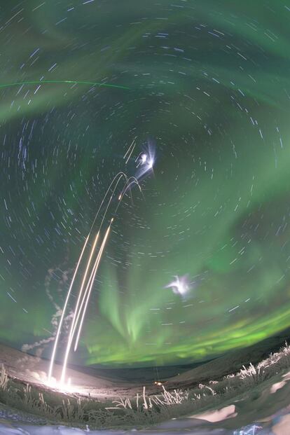 Un cohete lanzado con una aurora boreal de fondo.