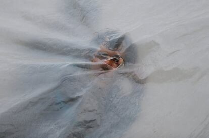Un emigrante venezolano mira a través de un agujero en el plástico de una carpa, en un asentamiento improvisado cerca de Bogotá (Colombia), el 13 de noviembre de 2018.